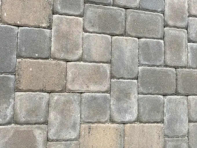 Close view of tumbled gray concrete pavers in a random three piece pattern