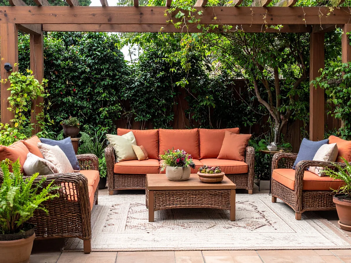 Tan paver patio under a wood pergola with outdoor seating